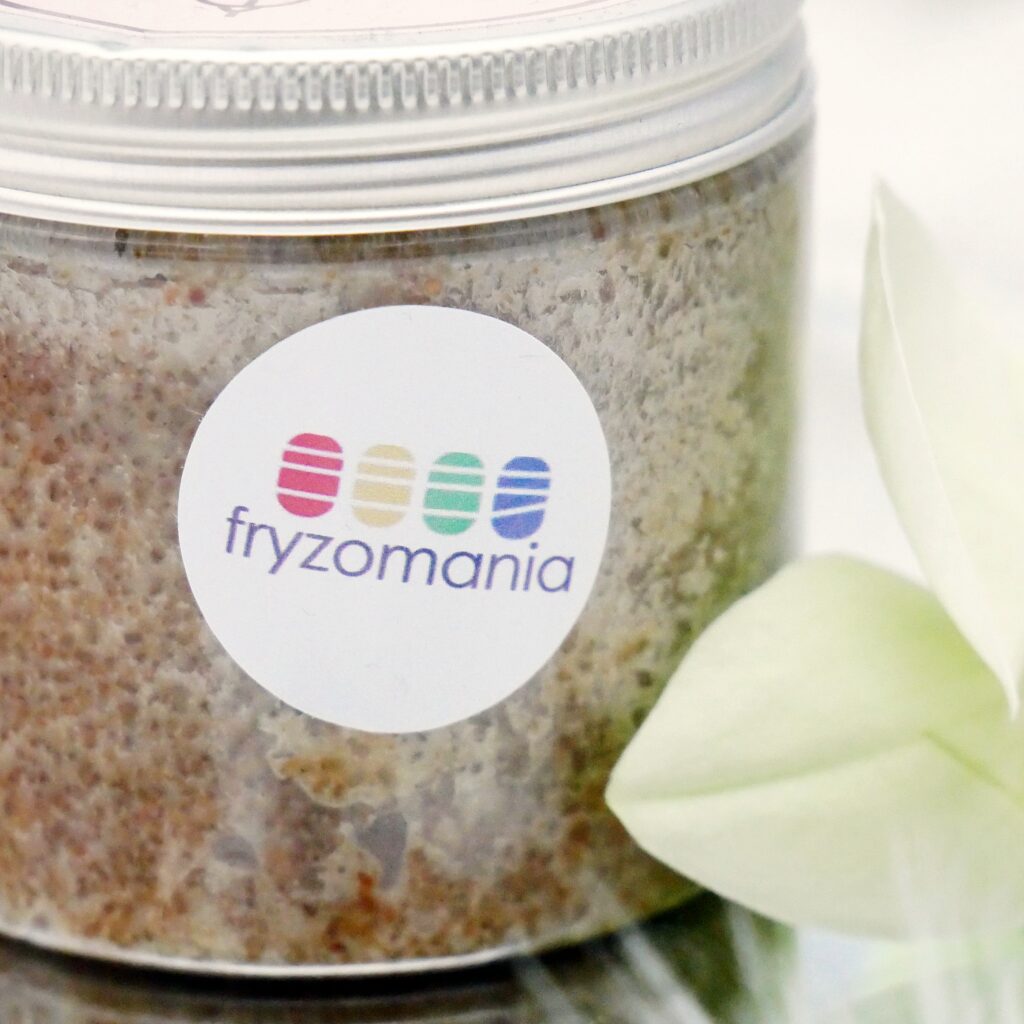 Zbliżenie na logo sklepu fryzomania.pl, naklejone na opakowaniu peelingu cukrowego róża i baobab.