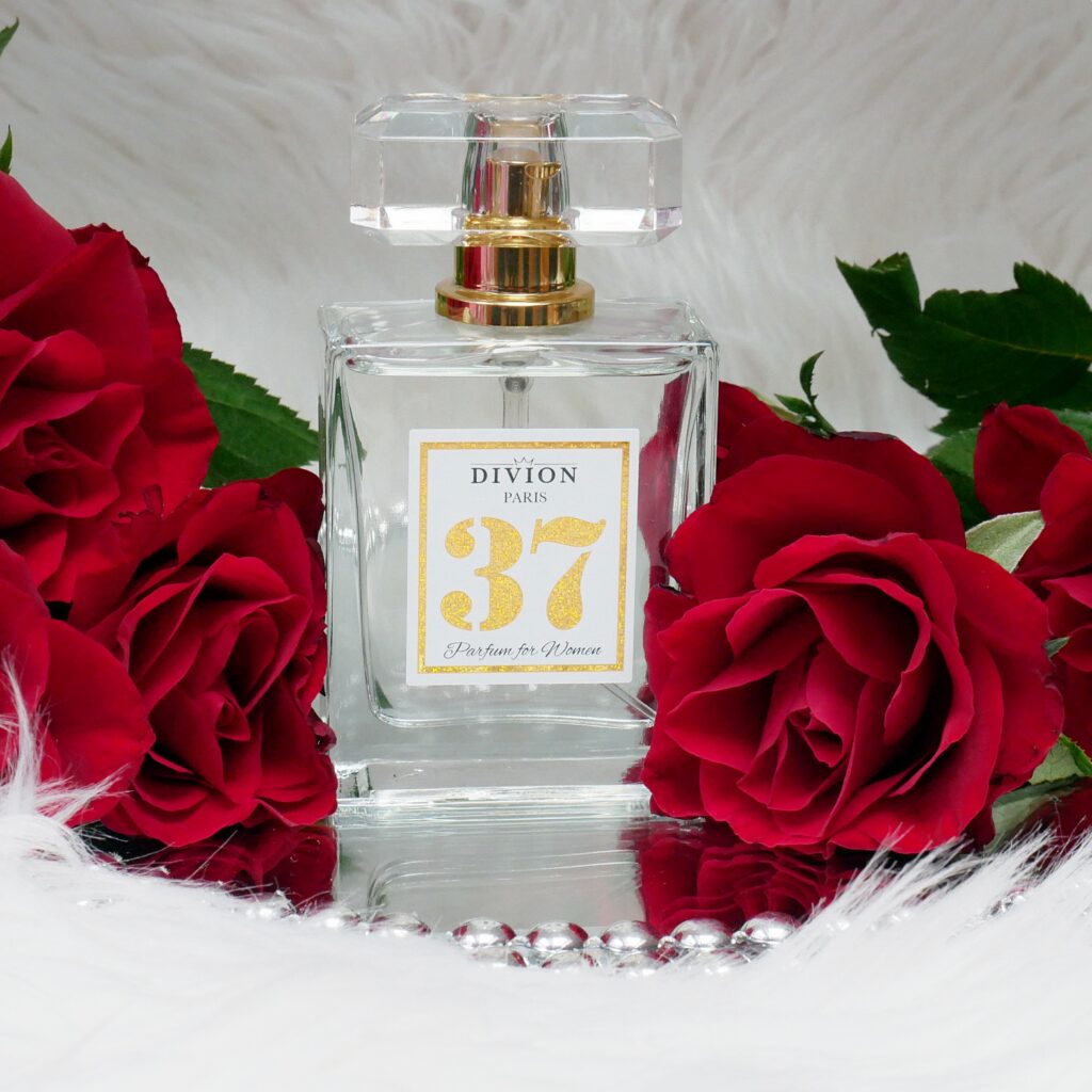 Lane perfumy Divion 37 – elegancka kompozycja z różami na lustrze Lane perfumy Divion 37 stojące na lustrze obok czerwonych róż.