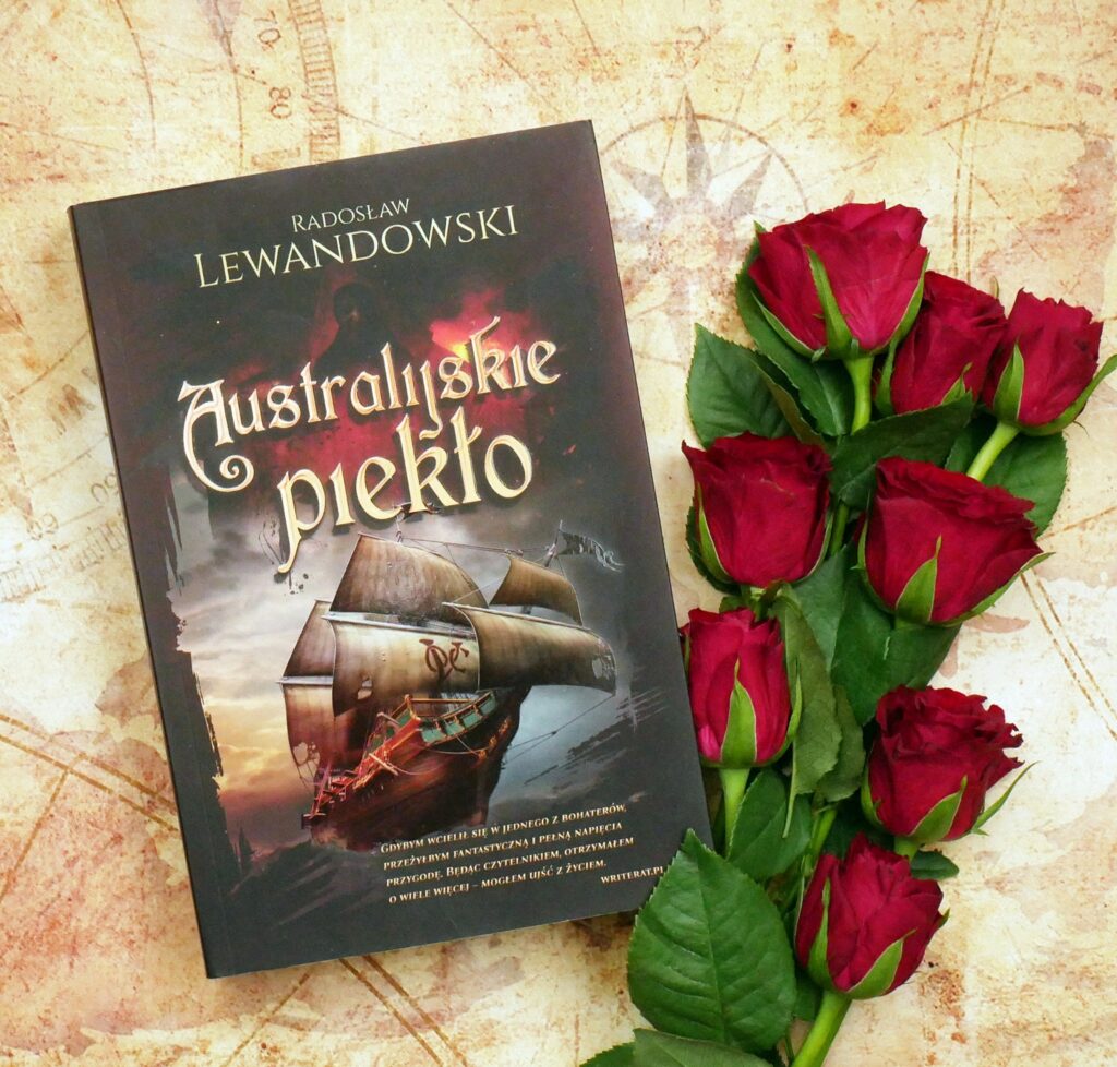 Radosław Lewandowski „Australijskie piekło” - recenzja Okładka książki „Australijskie piekło” Radosława Lewandowskiego z ilustracją dawnego żaglowca, leżąca na tle starej mapy w otoczeniu czerwonych róż.