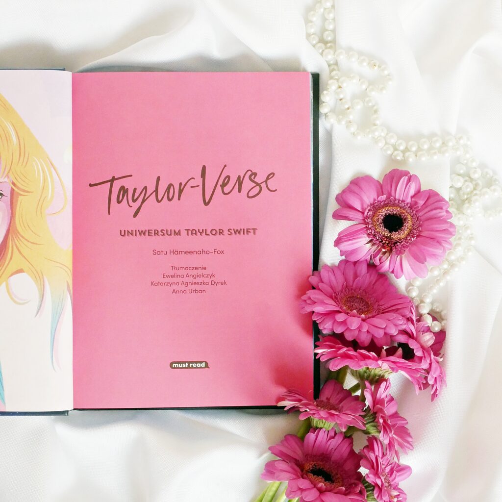 Strona tytułowa książki „Taylor-Verse” autorstwa Satu Hameenaho-Fox Strona tytułowa książki „Taylor-Verse” autorstwa Satu Hameenaho-Fox. Obok leżą perły i różowe gerbery