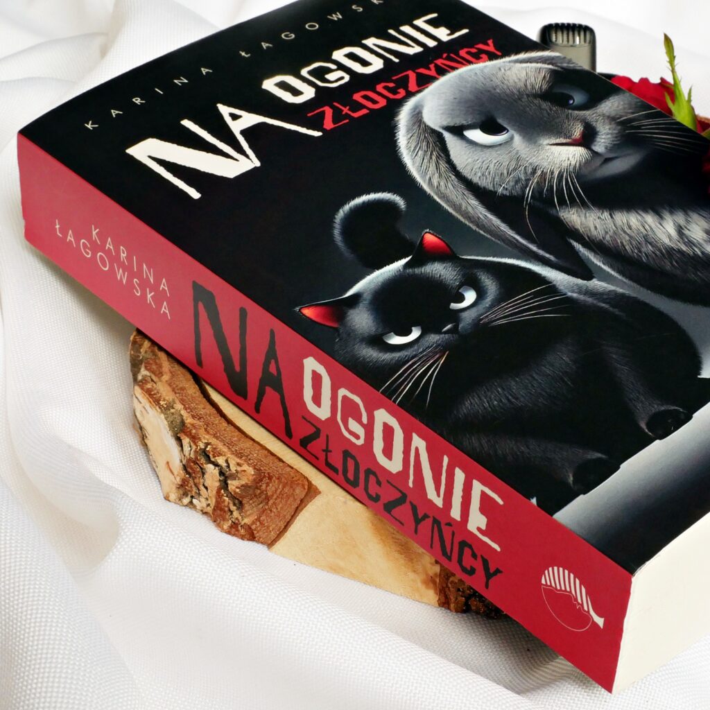 Grzbiet i okładka książki „Na ogonie złoczyńcy” autorstwa Kariny Łagowskiej. W tle mikrofon i czerwone róże.