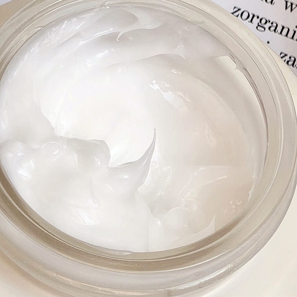 Zbliżenie na gęstą, białą formułę kremu nawilżającego z czarnym ryżem i ceramidami.