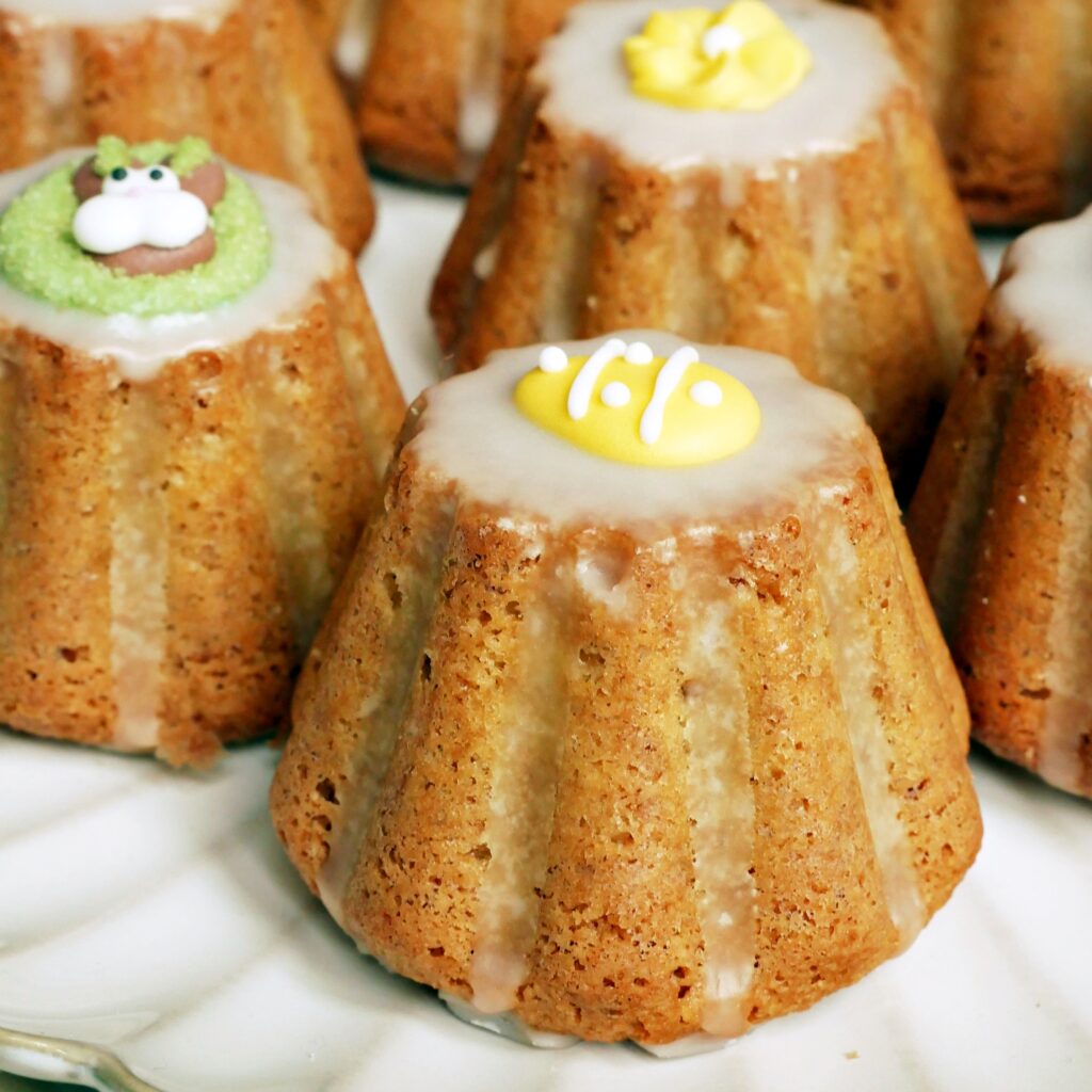 Zbliżenie na puszystą strukturę babeczki migdałowej z lukrem i cukrową ozdobą w kształcie pisanki.