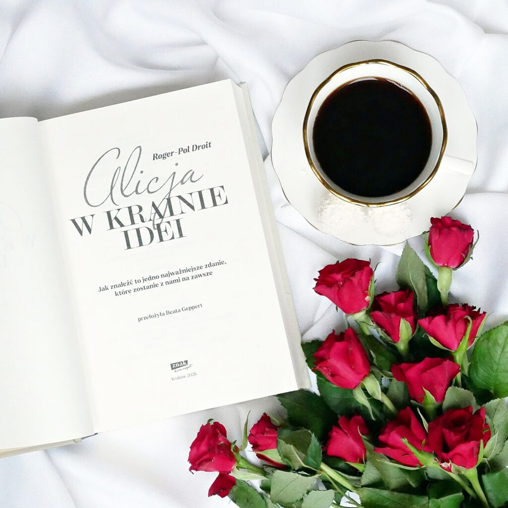 Strona tytułowa książki Alicja w Krainie Idei” autorstwa Rogera-Pola Droita leżąca na białym materiale obok filiżanki czarnej kawy i czerwonych róż.