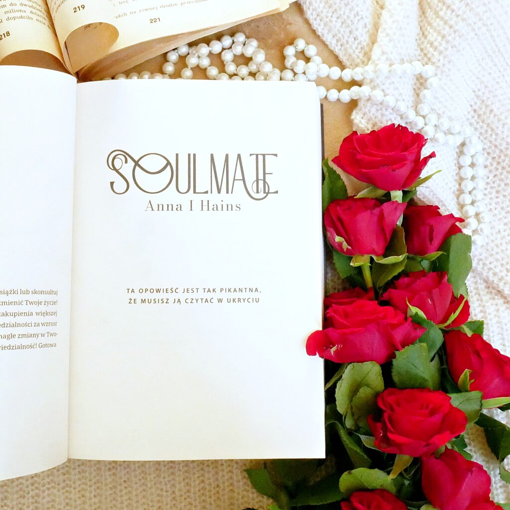 Strona tytułowa książki „Soulmate” autorstwa Anny I. Hains Strona tytułowa książki „Soulmate” Anny I. Hains w otoczeniu czerwonych róż, pereł i starej książki.