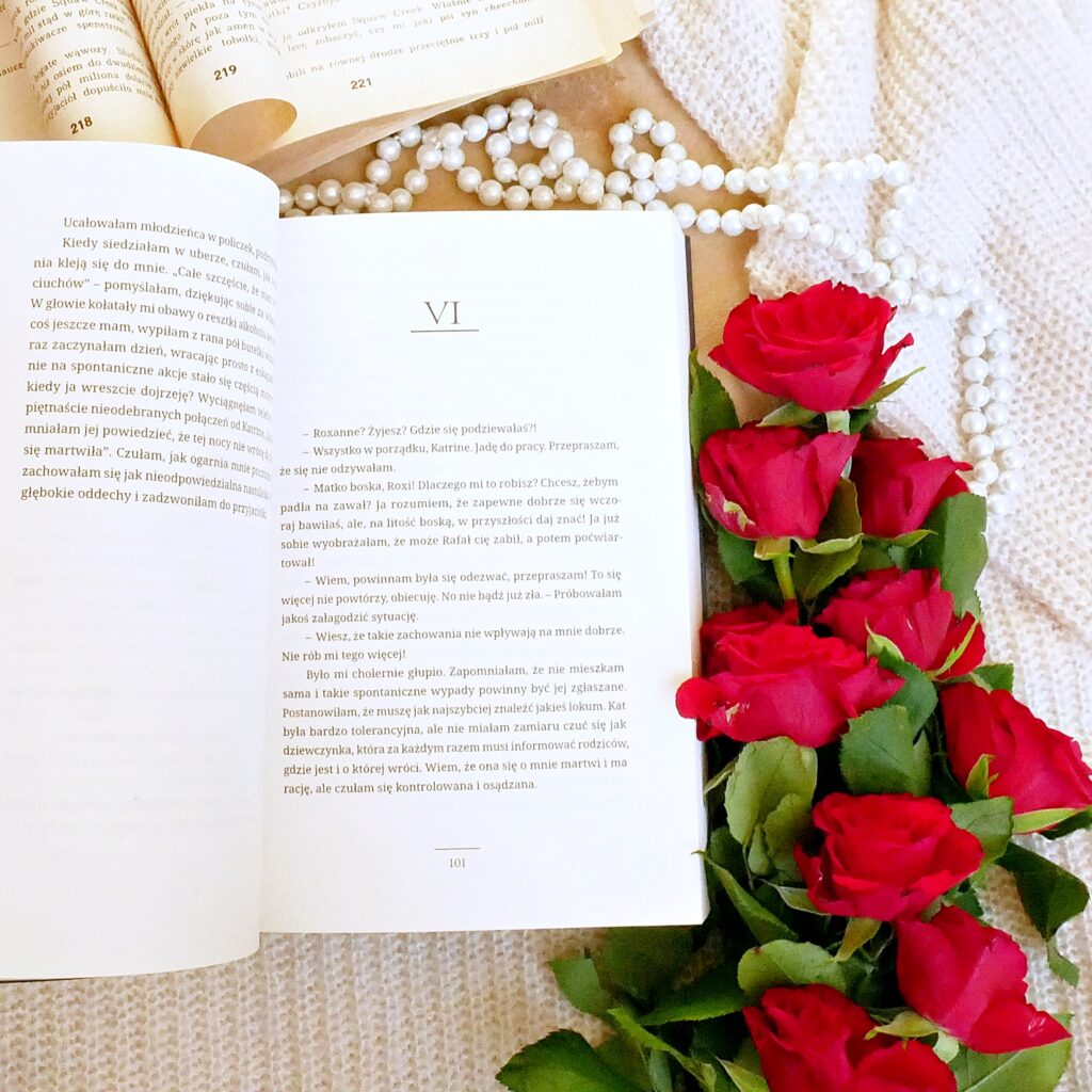 Wnętrze książki „Soulmate” Anny I. Hains- Rozdział 6 Rozdział 6 książki „Soulmate” w otoczeniu czerwonych róż, pereł i starej książki.