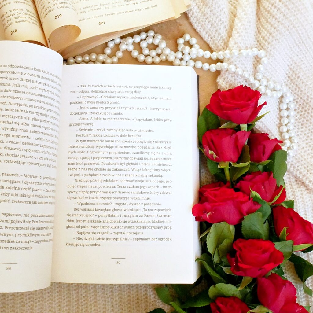 Fragment recenzowanej książki „Soulmate” Anny I. Hains Fragment tekstu z książki Anny I. Hains „Soulmate”. Obok leżą czerwone róże, perły i stara książka.