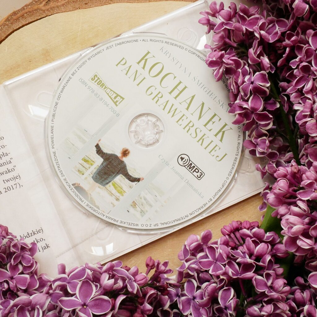 Krystyna Śmigielska „Kochanek pani Grawerskiej” - wydanie CD Płyta CD „Kochanek pani Grawerskiej” Krystyny Śmigielskiej w otwartym, przezroczystym etui na tle kwiatów.
