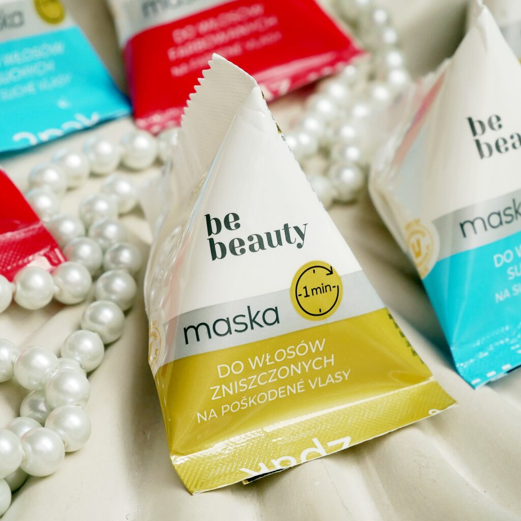 unkcjonalny design i minimalistyczne opakowanie maseczki Be Beauty Zbliżenie na trójkątne opakowanie maski do włosów Be Beaut. Aranżacja z czerwonymi różami i perłami na dekoracyjnej misie.