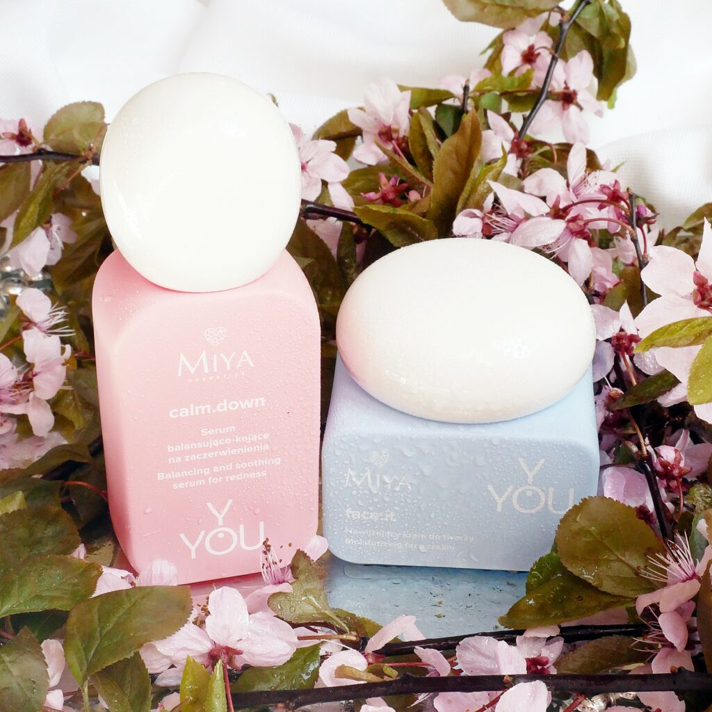 Miya Cosmetics Y.YOU – Minimalistyczny design i funkcjonalność. Serum balansująco-kojące i krem nawilżający Miya Cosmetics Y.YOU w otoczeniu różowych kwiatów.