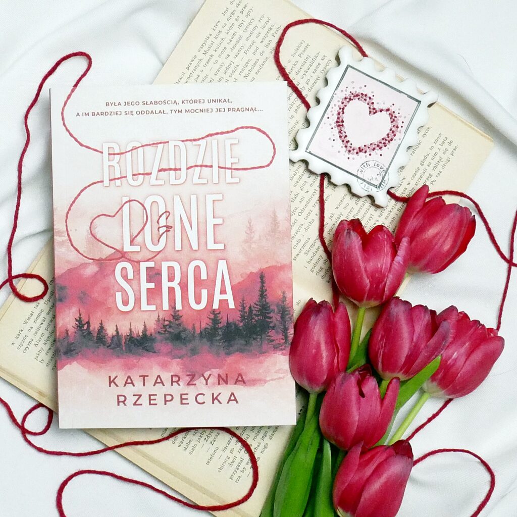 Recenzja książki Katarzyny Rzepeckiej „Rozdzielone-serca” Okładka książki „Rozdzielone serca” Katarzyny Rzepeckiej. Aranżacja z czerwonymi tulipanami, czerwoną włóczką i piernikiem w kształcie znaczka pocztowego z sercem.