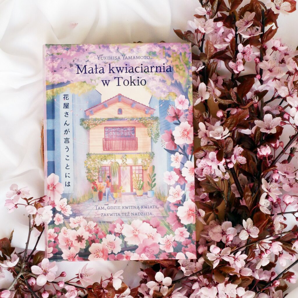 Recenzja książki „Mała kwiaciarnia w Tokio” Yukihisa Yamamoto Okładka książki „Mała kwiaciarnia w Tokio” Yukihisa Yamamoto w otoczeniu różowych kwiatów wiśni.
