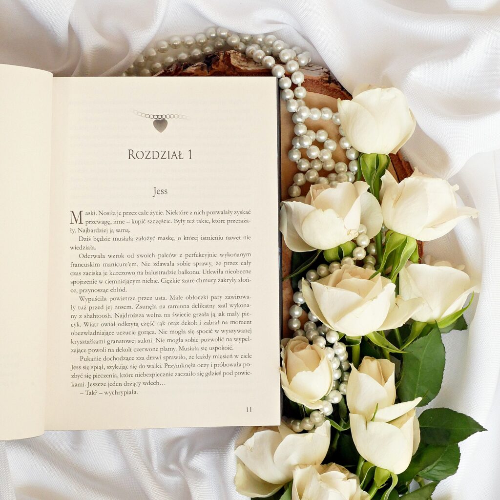 Rozdział pierwszy zatytułowany „Jess”, w eleganckim kadrze z książką na plastrze drewna, perłami i białymi różami.