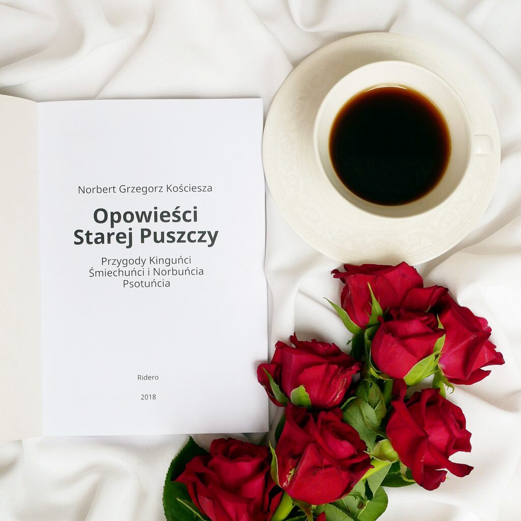Strona tytułowa książki z napisem Norbert Grzegorz Kościesza „Opowieści starej puszczy” na białym materiale w otoczeniu czerwonych róż i filiżanki kawy.